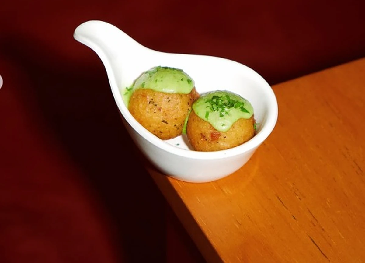 Bolinho de arroz com maionese verde servido em colher de porcelana