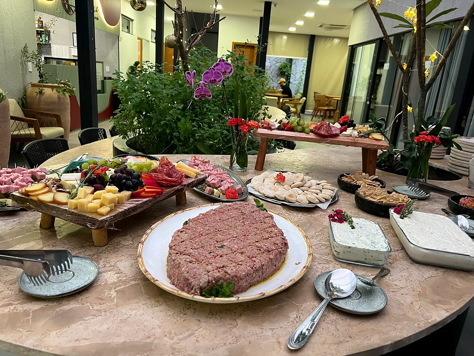 Mesa de buffet do Lumne com frios, pães e acompanhamentos